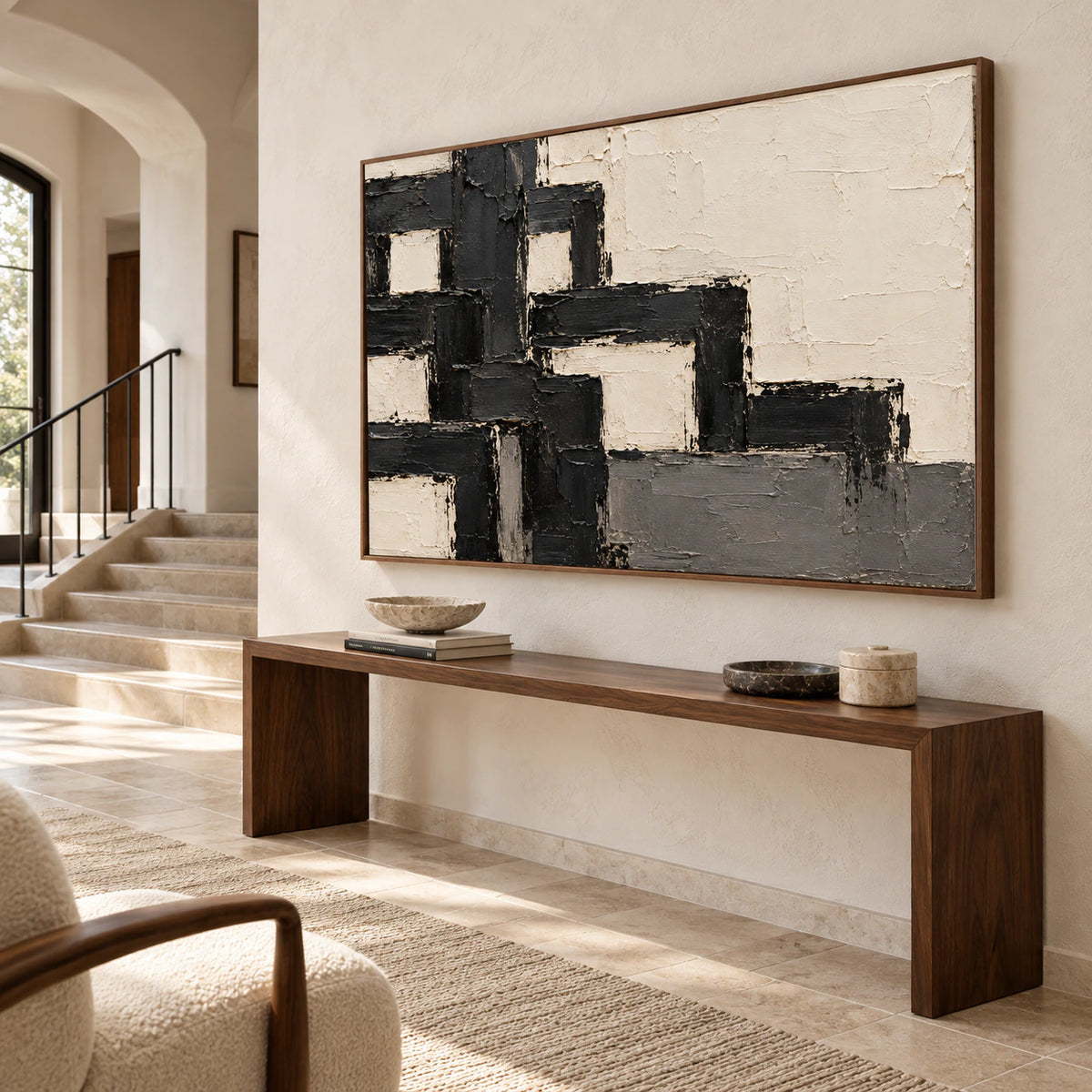 Large ivory and charcoal abstract painting on a tall warm white foyer wall, viewed from an elevated left angle with a stair landing, pale stone floor and narrow console.