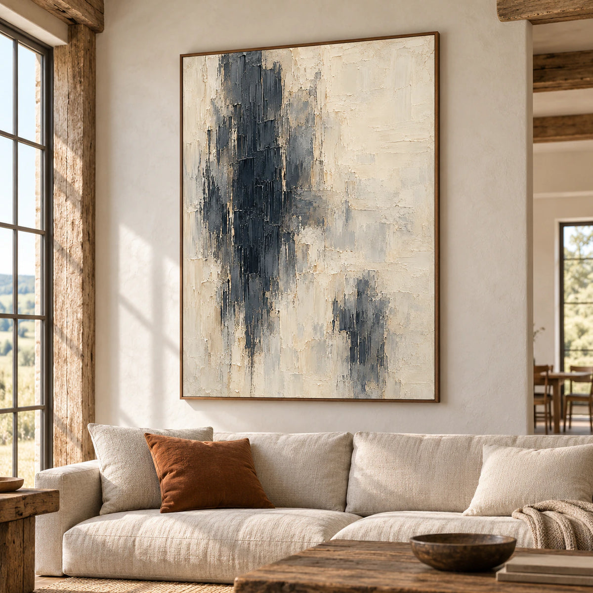 Obsidian-Pillars above a low neutral sofa in a bright living room with tall windows, pale plaster walls, and simple timber furniture.