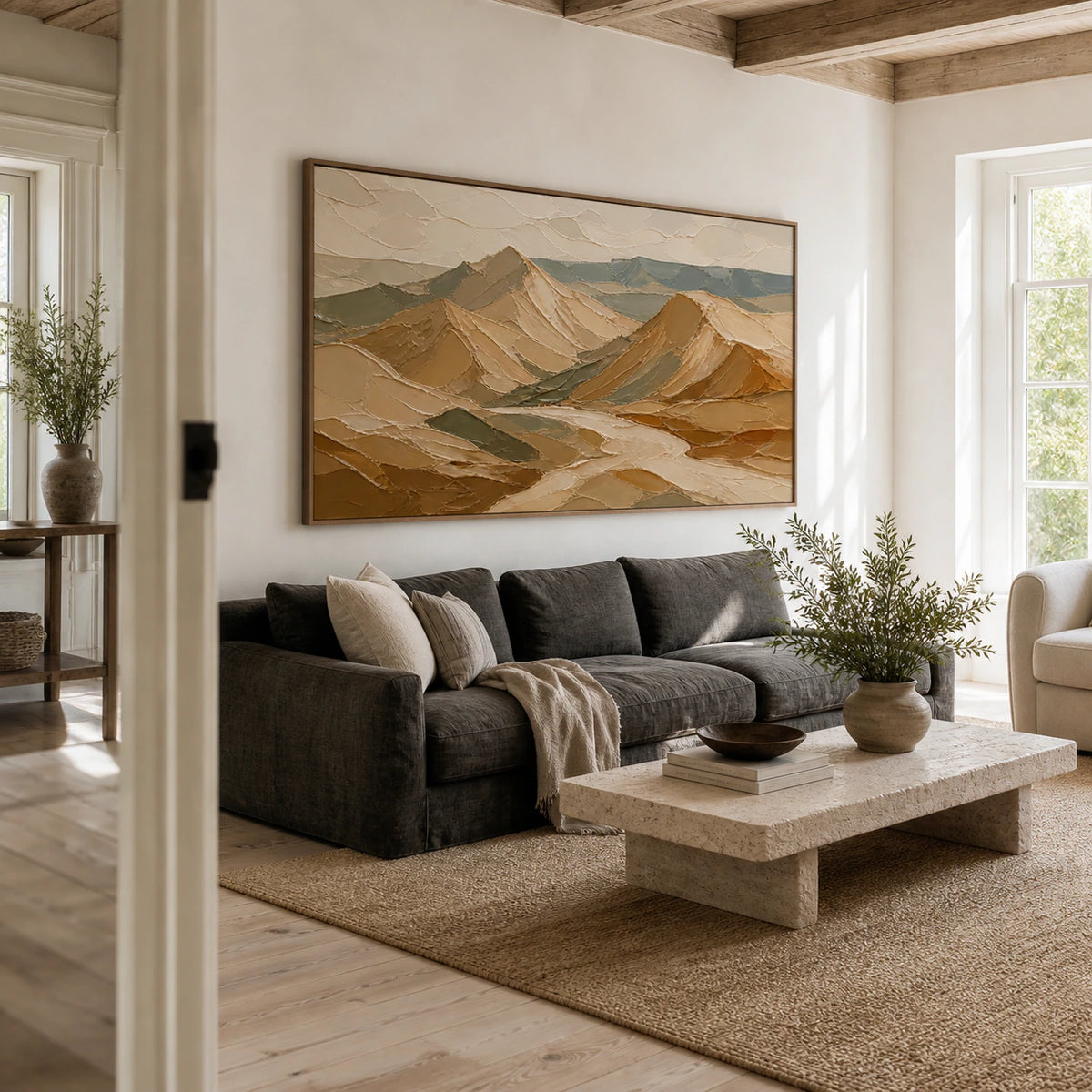 Ochre and blue-green abstract mountain painting above a sofa in a bright living room.
