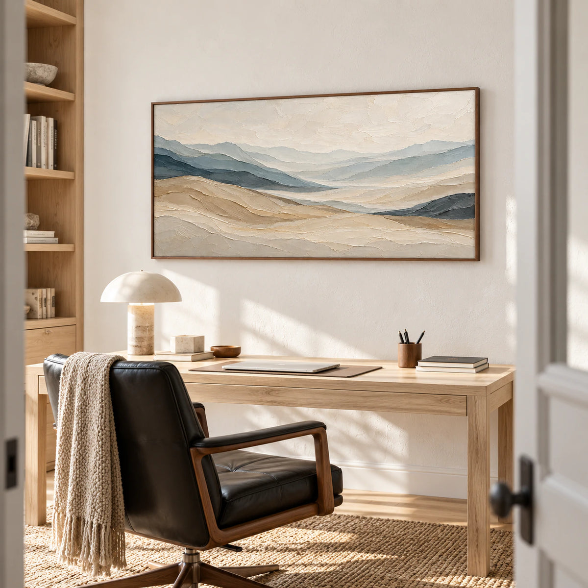 Ochre-Traverse above a pale desk in a bright home office with a black leather reading chair, open shelving and a sculptural lamp, viewed from the right.