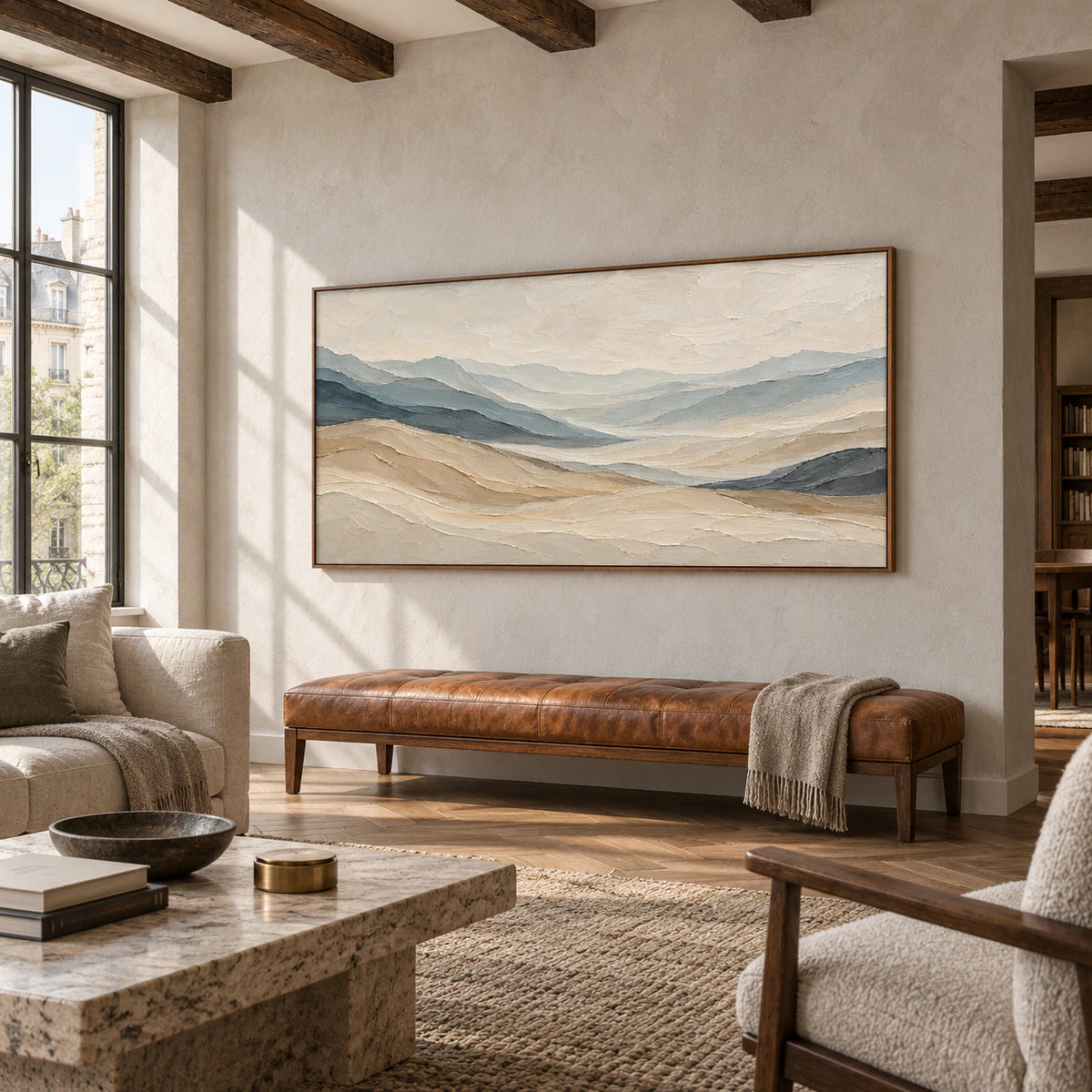 Ochre-Traverse above a cognac leather bench on a light gray wall in a spacious loft lounge with dark timber beams and a broad window, viewed from the right.