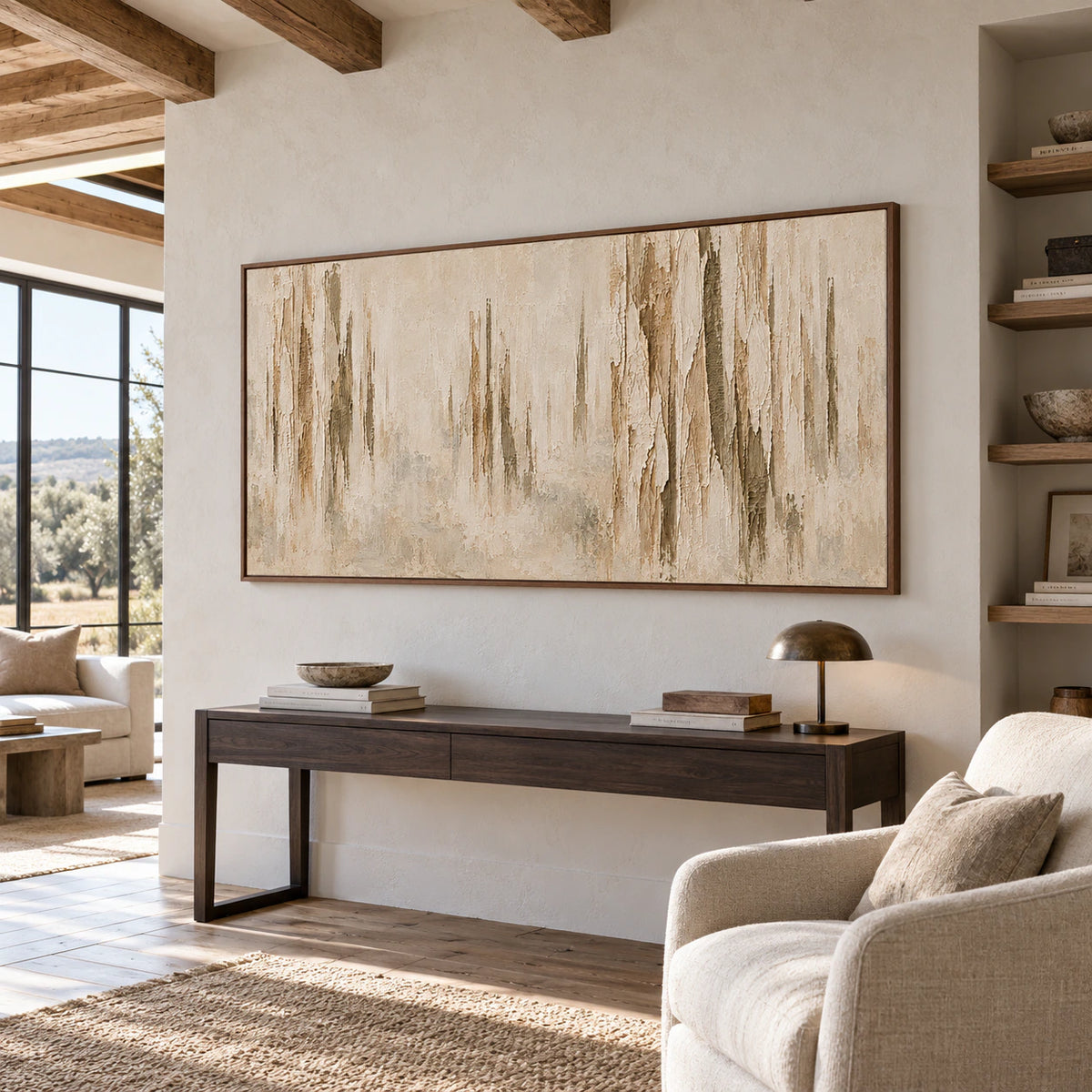 Wide painting anchoring an airy home office and reading space, with a dark desk, pale walls and clear natural daylight.