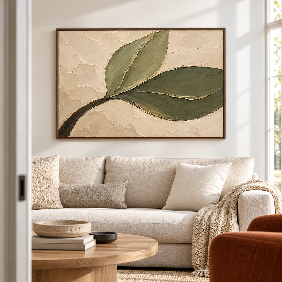 Olive-Sweep painting above a pale sofa in a bright living room with broad windows, viewed slightly from the left at seated eye level.