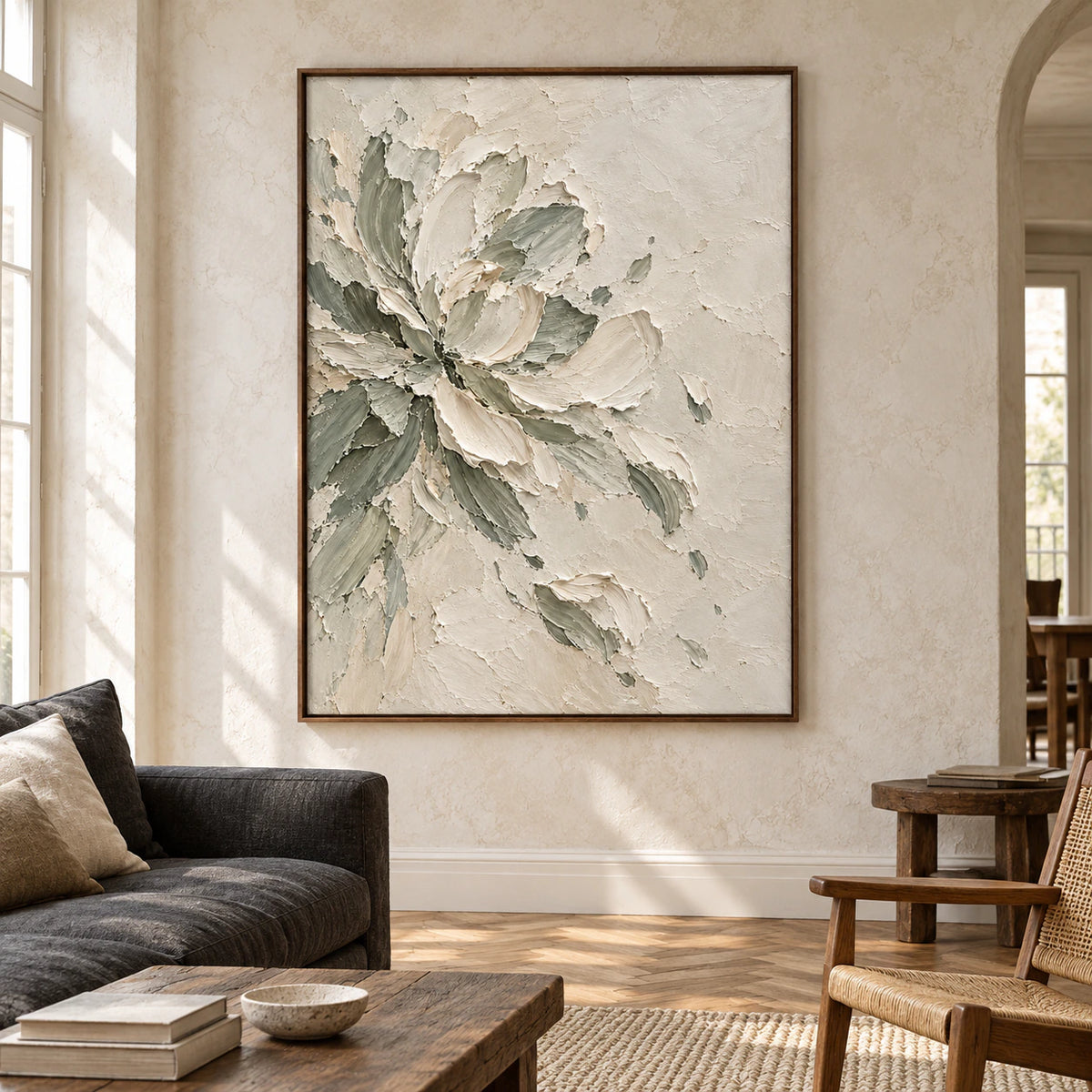 Large floral artwork above a charcoal sofa in a bright living room with pale walls, natural daylight and restrained furnishings.
