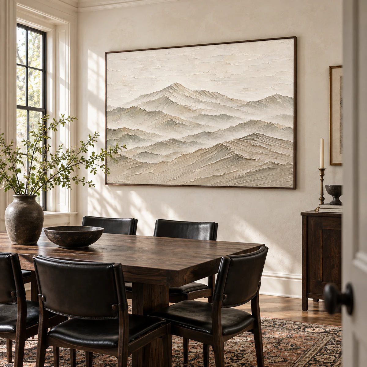 Layered mountain artwork in a refined daylight dining room.