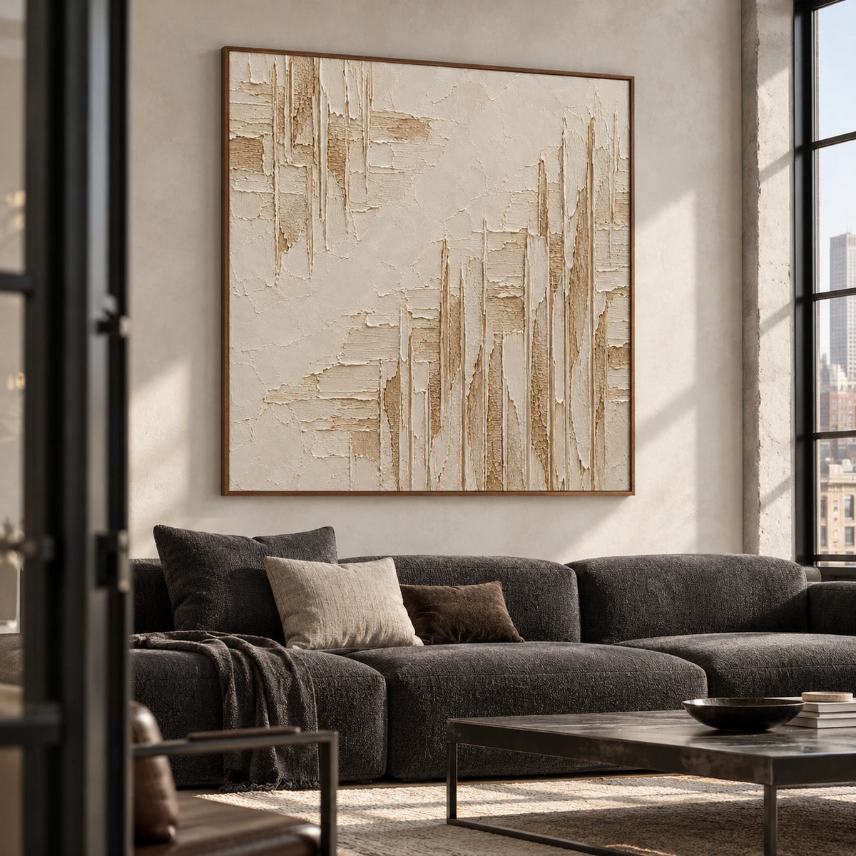 Large square textured artwork above a restrained charcoal sofa in a bright living room.