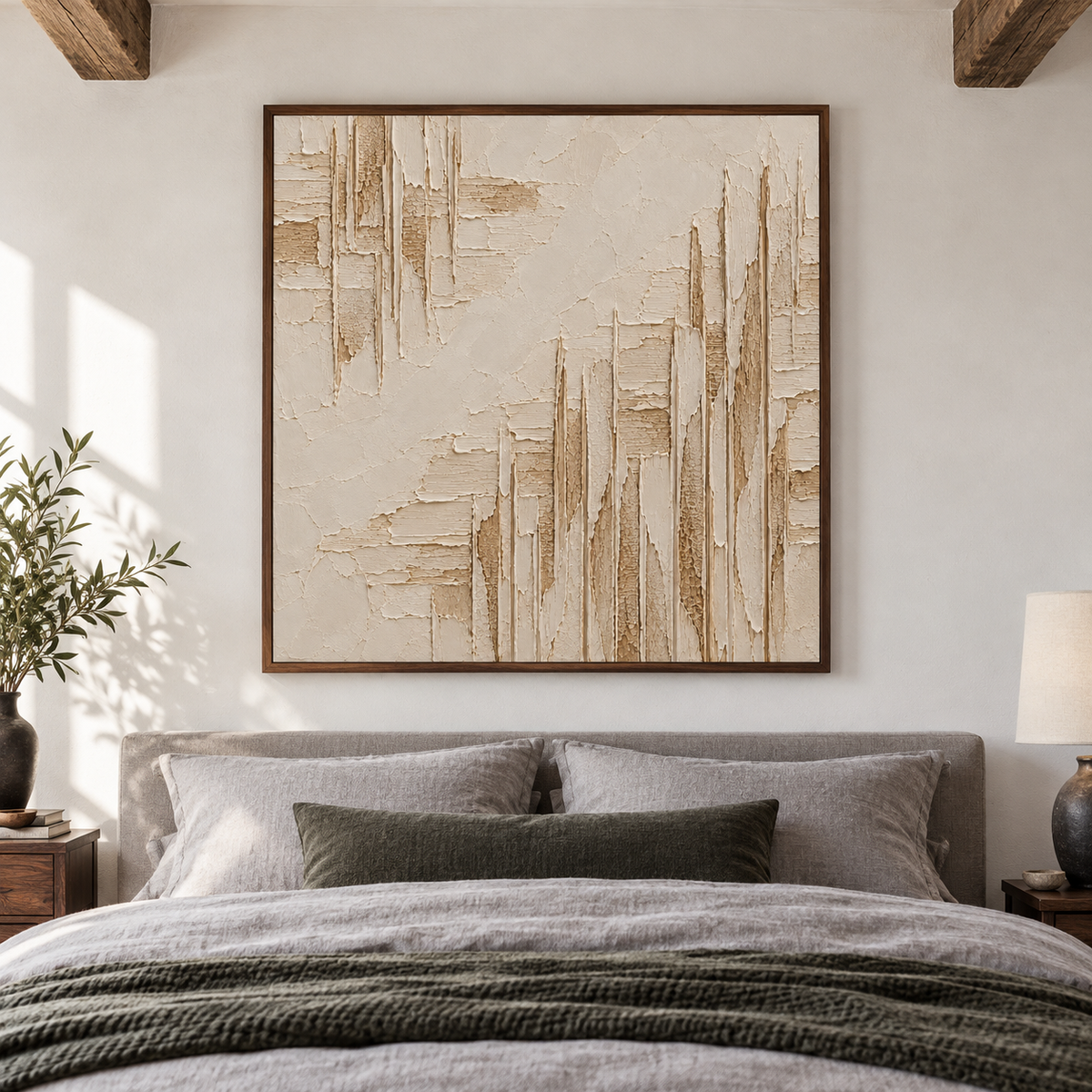 Textured square artwork above a low bed in a quiet, sunlit bedroom with muted gray linens.