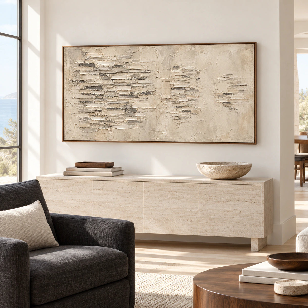 Large horizontal abstract painting with ivory and gray textured bands above a pale stone console in a bright living room.