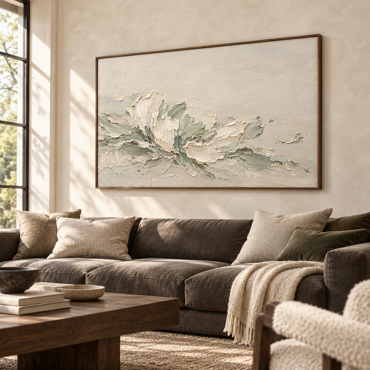 Ivory and sage abstract painting above a charcoal sofa against a pale plaster wall in a bright living room, viewed from the left.
