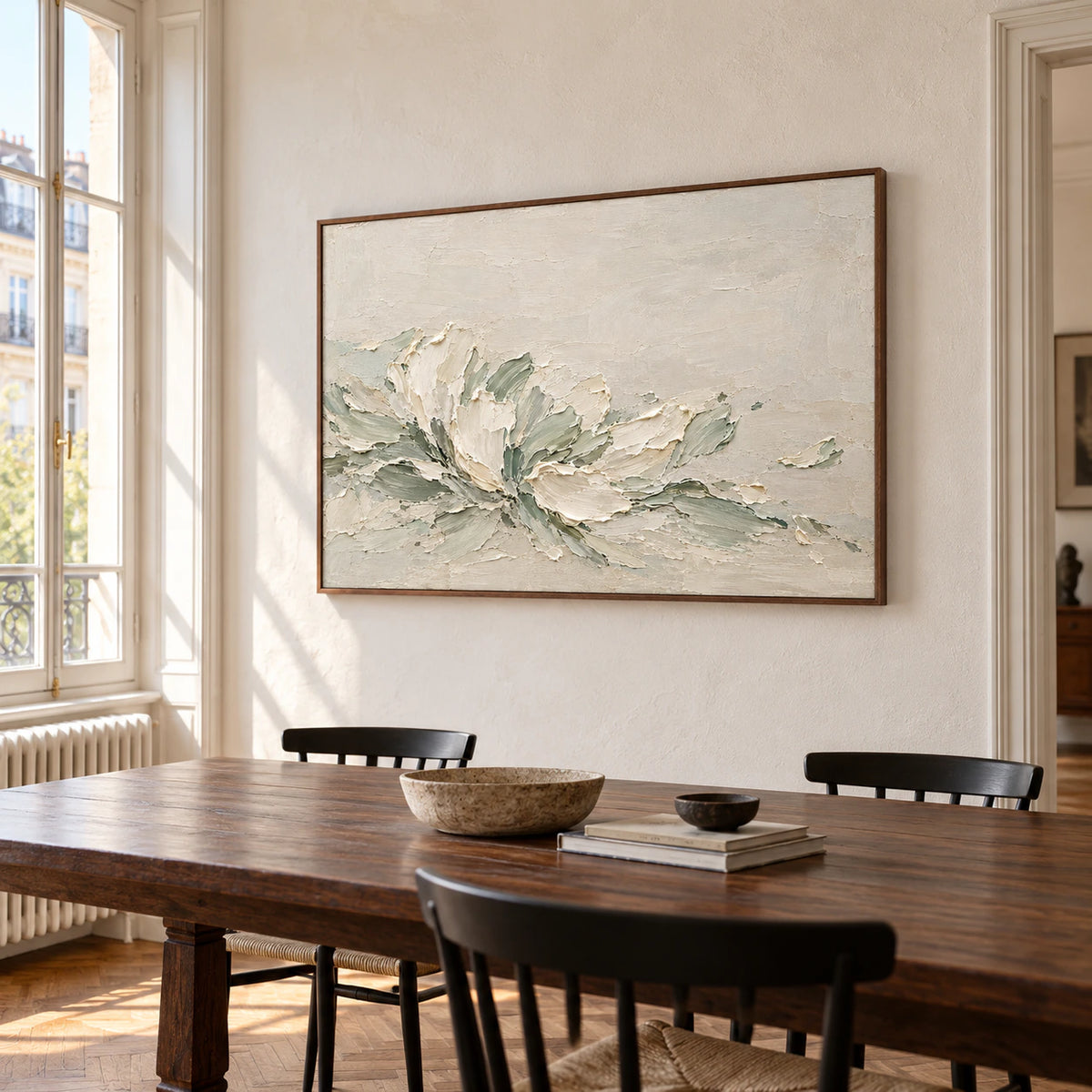 Ivory and sage abstract painting on a warm white dining room wall beside a dark walnut table and black chairs, viewed from the right.