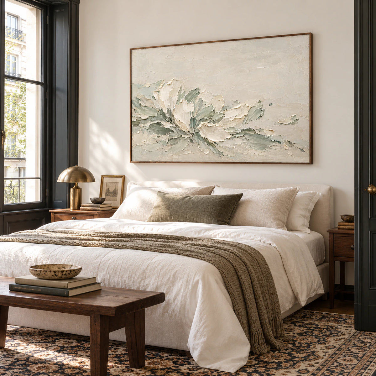 Ivory and sage abstract painting above a low bed with white bedding and dark timber accents, viewed from a slightly elevated left angle.