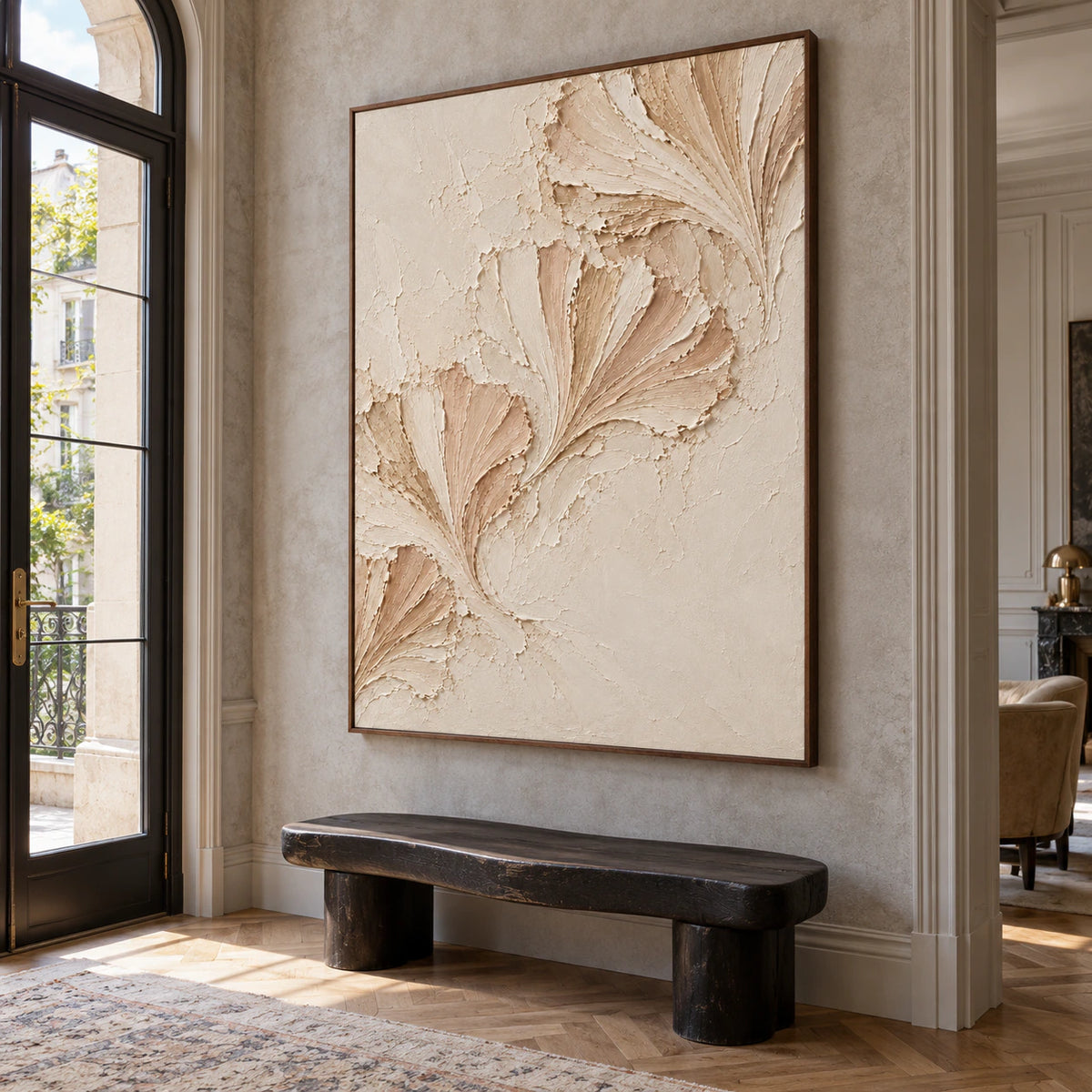 Petal-Folds on a tall cool gray stone wall in an open foyer with a sculptural black bench and glazed entry, viewed from a low left angle.