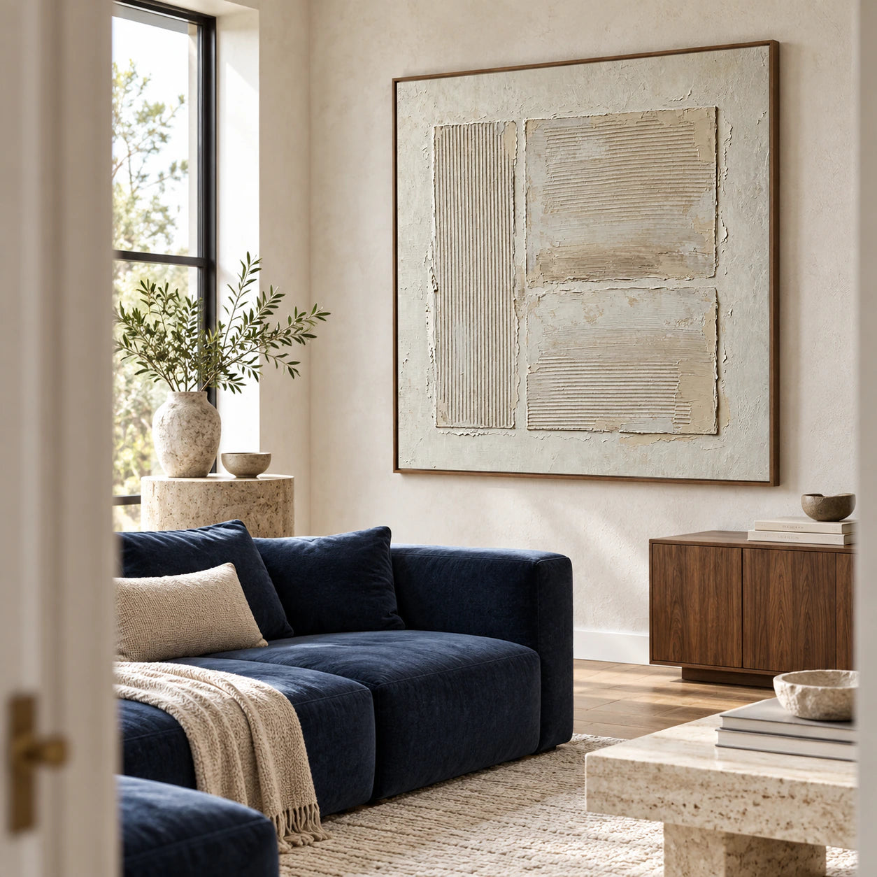 Square ivory textured artwork above a bright contemporary living room seating area.