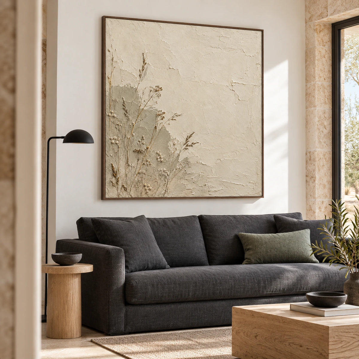 Square botanical plaster artwork above a sofa in a bright, open living room.