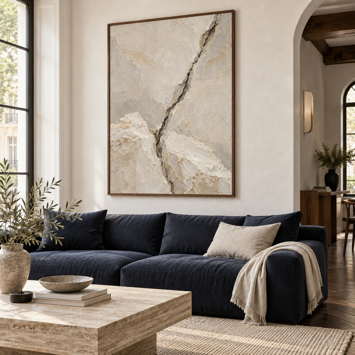 Vertical textured abstract painting above a restrained sofa in a bright living room.