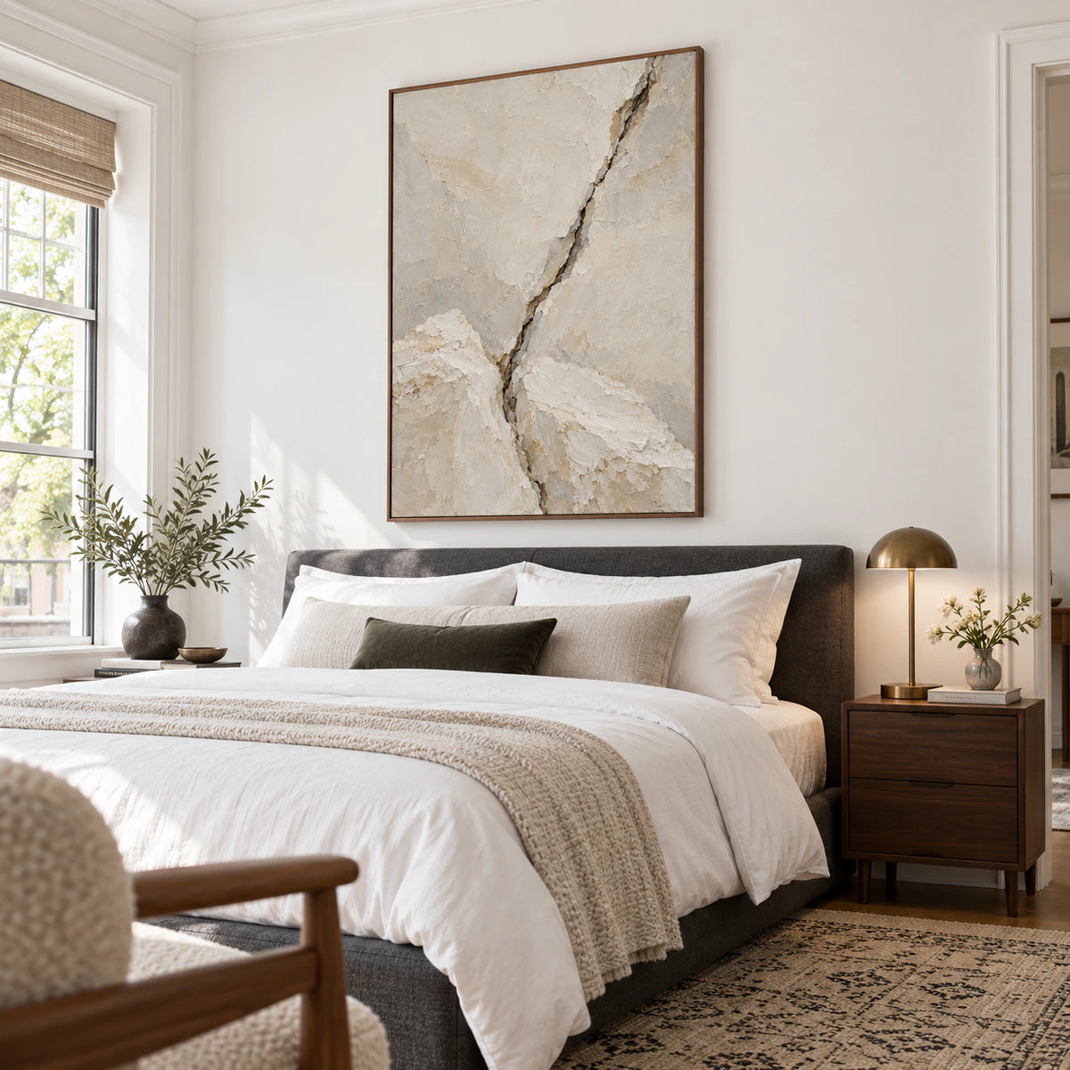Textured neutral abstract painting above a bed in a quiet, sunlit bedroom.