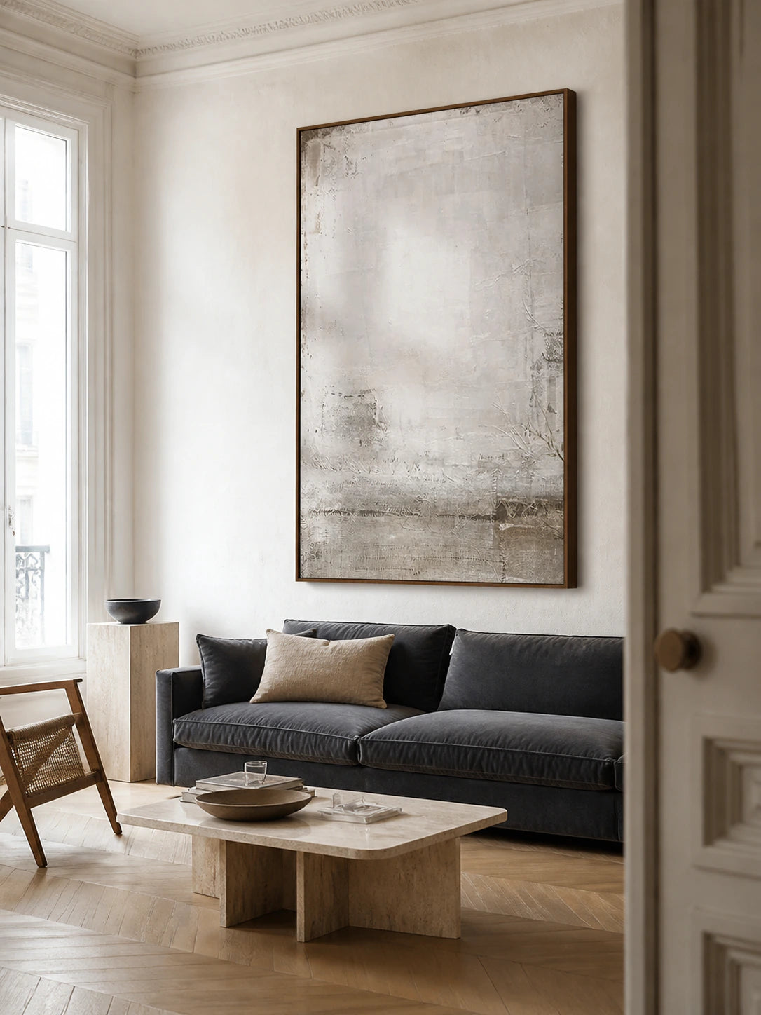 Pale textured abstract painting above a sofa in a bright contemporary living room.