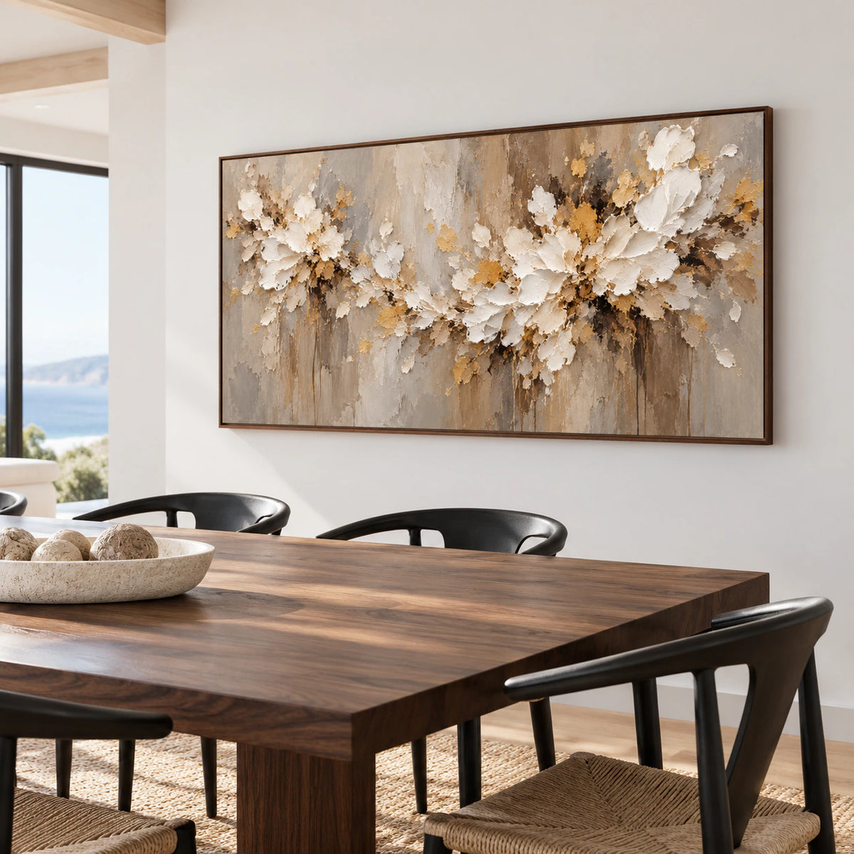 Right oblique view of a large horizontal ivory floral painting on a cool pale wall behind a dark walnut dining table and sculptural black chairs in daylight.