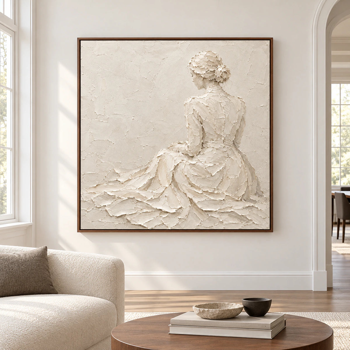 Large square ivory relief artwork showing a seated figure from behind, centered on a broad pale wall in a spacious modern room.