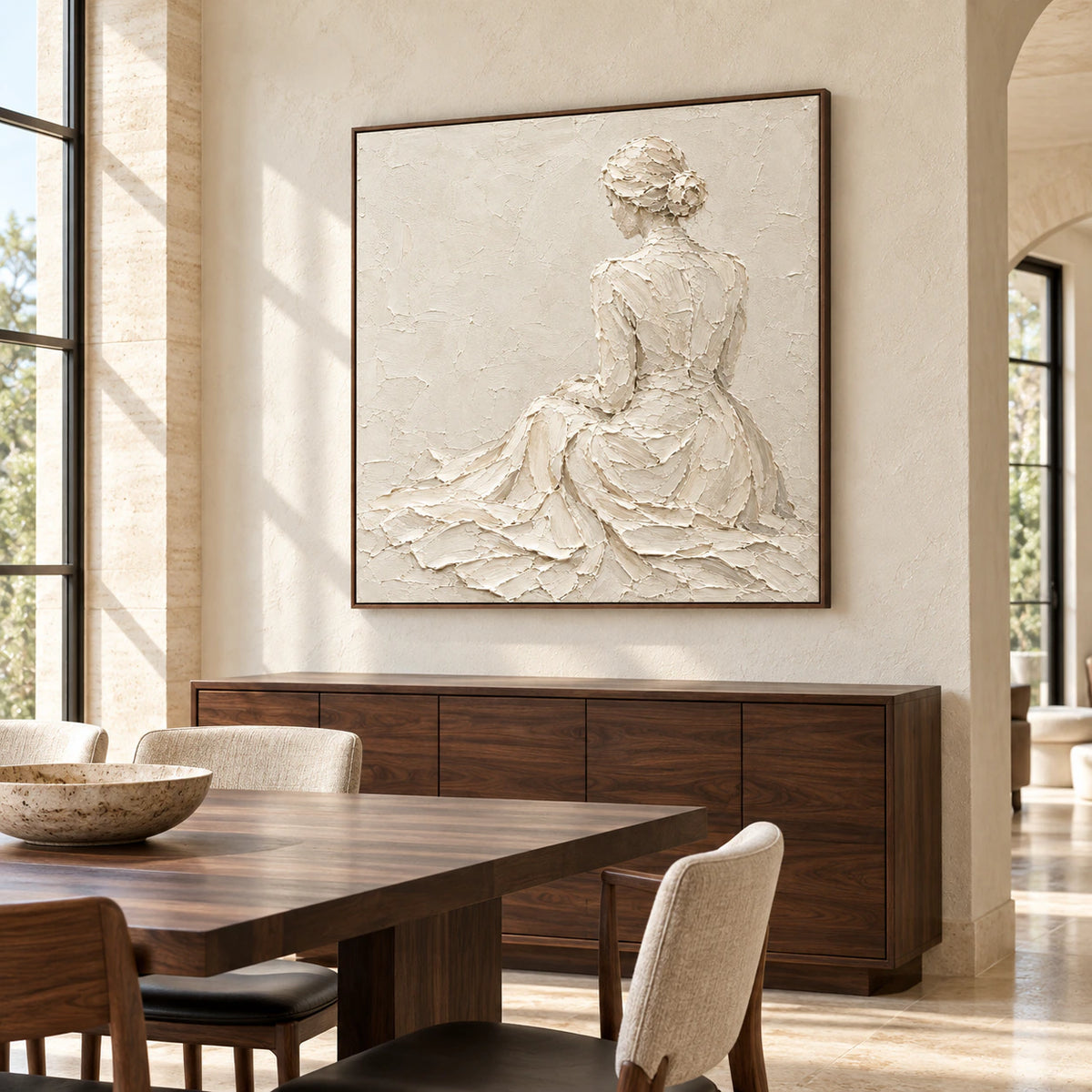 Square ivory relief artwork above a dark wood dining sideboard in a bright dining room with tall windows and restrained furnishings.