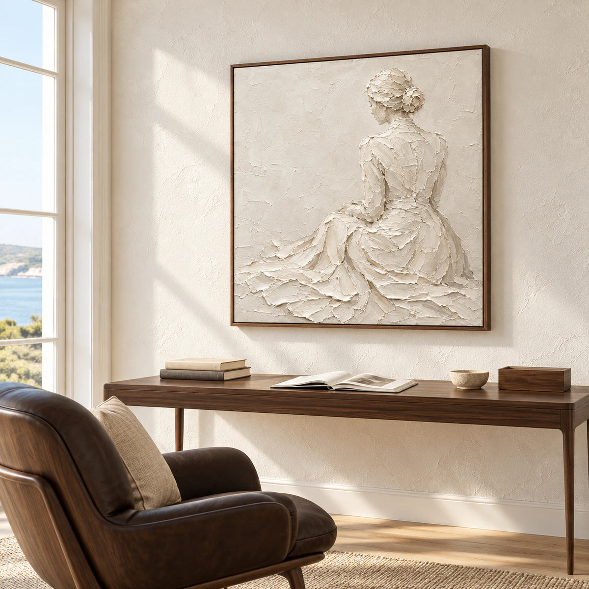 Square ivory textured artwork above a slim desk in an airy home office with tall windows, warm wood, and a dark chair.