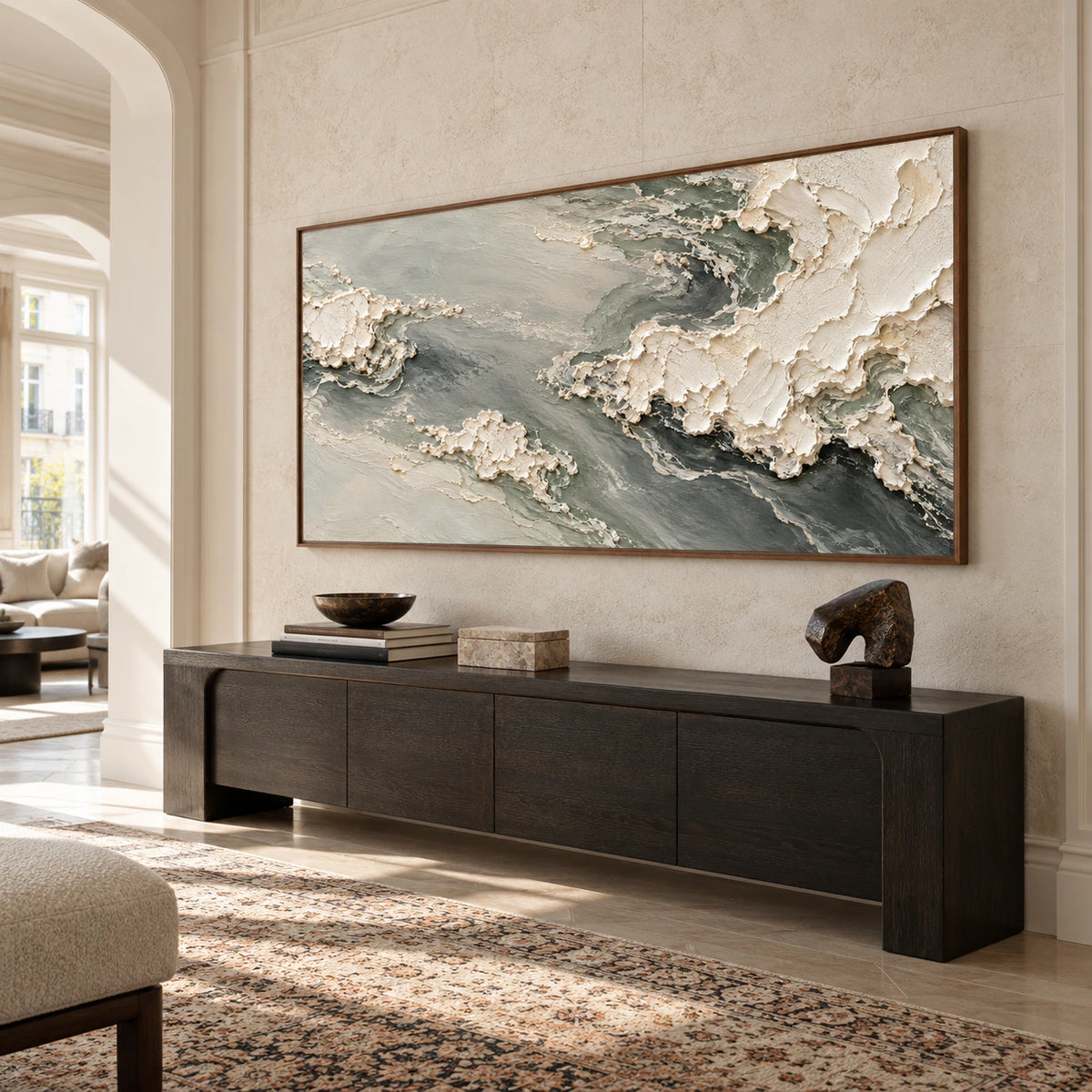 Pumice-Tide on a tall pale stone foyer wall above a dark wood console, viewed from a low, slightly left oblique angle in bright side daylight.
