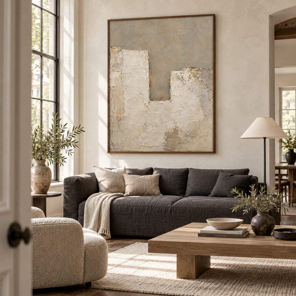 Textured neutral abstract artwork above a sofa in a bright living room.