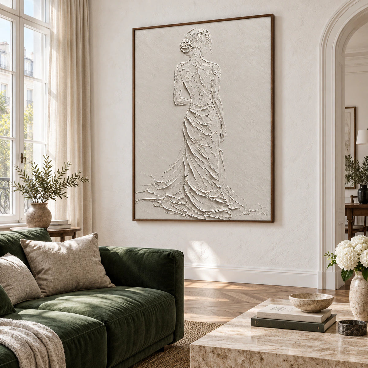 Ivory textured female figure wall art above a restrained sofa in a bright living room.