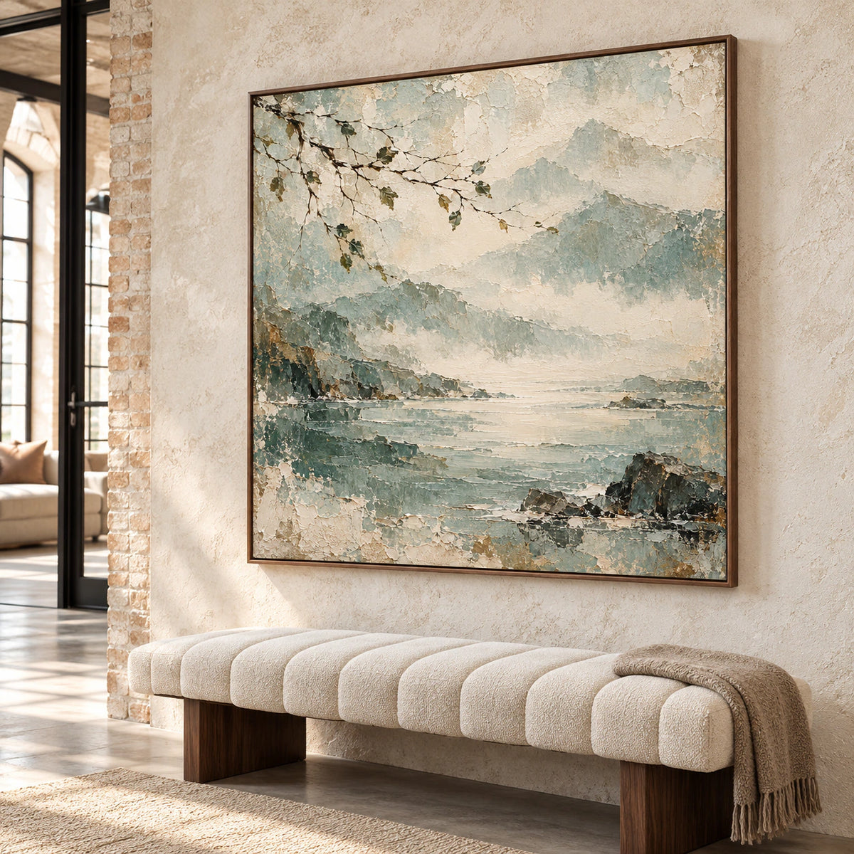 Gallery-scale foyer with the square coastal painting commanding a pale stone wall near a sculptural bench, viewed from the left at a modest upward angle.