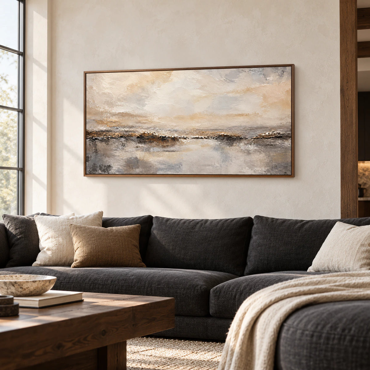 Large textured abstract horizon painting above a charcoal sofa in a bright living room with pale walls and daylight.