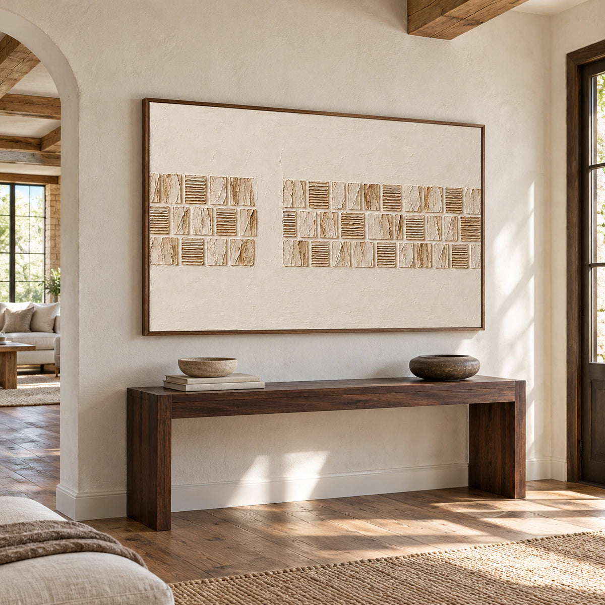 Large ivory relief painting on a pale stone foyer wall above a narrow dark console, viewed from a slightly elevated right angle with open floor space.