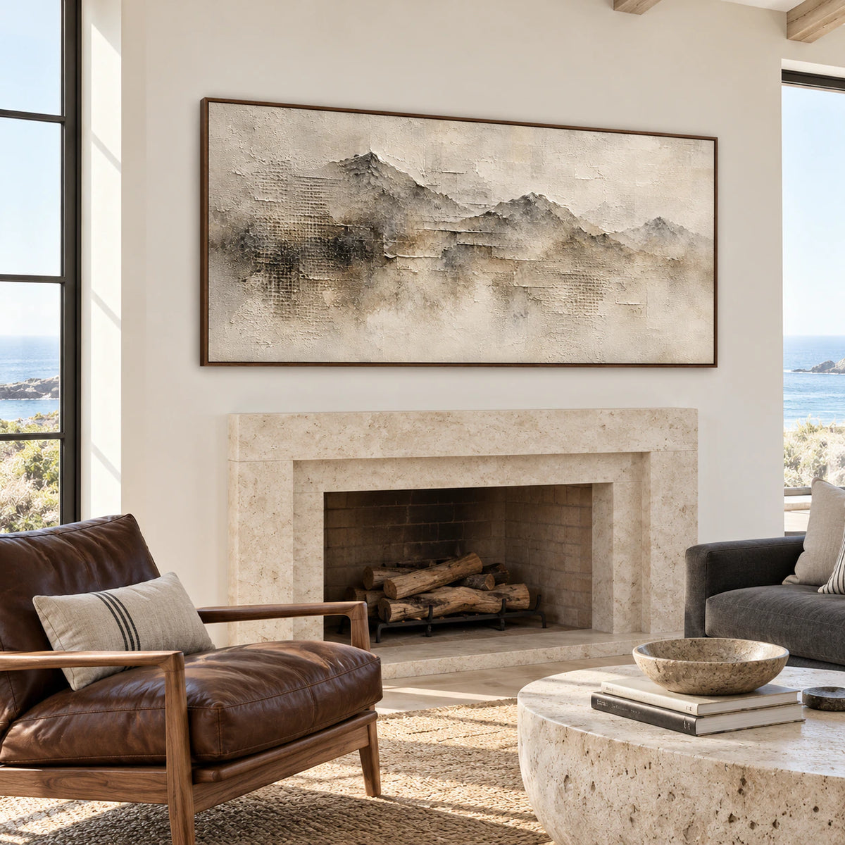 Panoramic ridgeline painting above a pale stone fireplace in a bright living room with a charcoal sofa, natural wood and tall windows, viewed straight on.