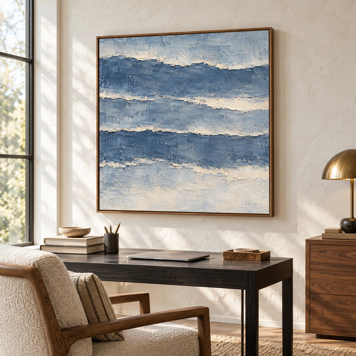 Riven-Tides painting on a pale wall near a black desk, reading chair, and tall window in a bright home office, viewed from the right.