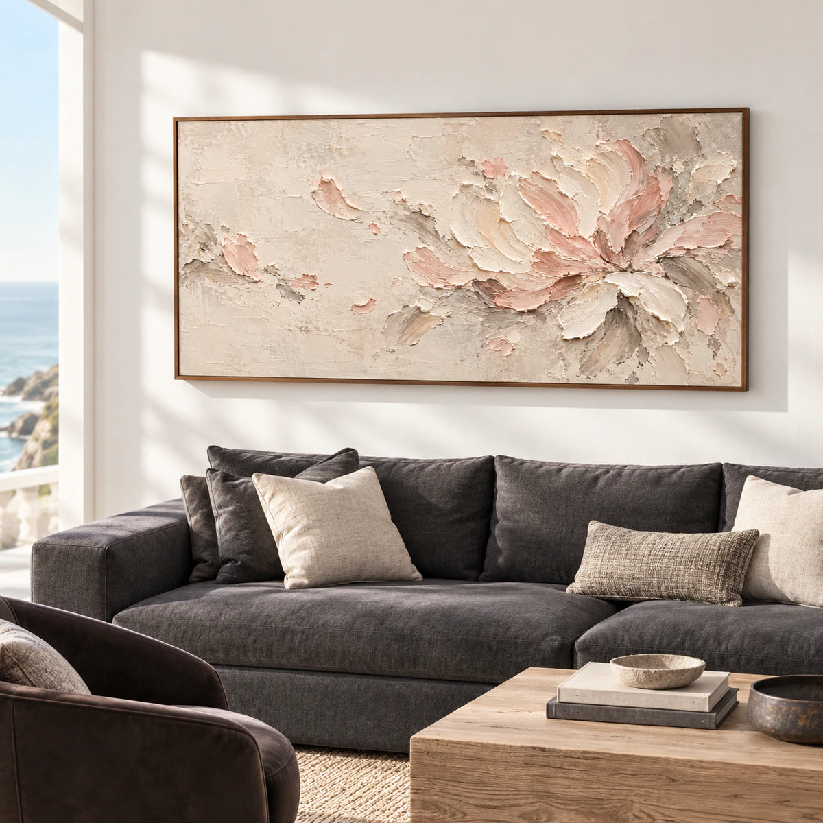 Ivory and blush floral abstract above a charcoal sofa in a bright, open living room, viewed from a gentle left angle.