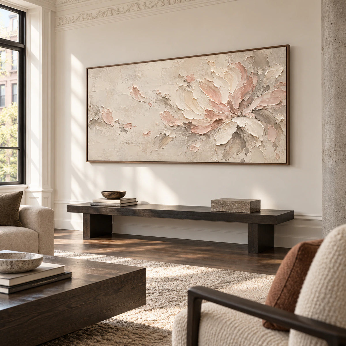 Ivory and blush floral abstract above a low dark bench in a spacious, daylit loft lounge with concrete columns, viewed from the right.