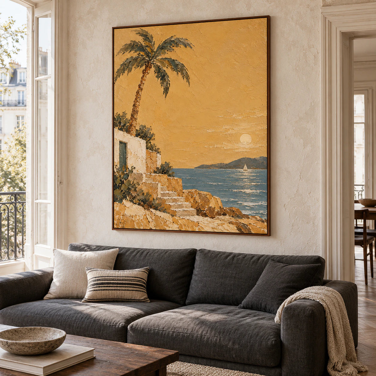 Vertical coastal painting above a low sofa in a bright living room with daylight and restrained neutral furnishings.