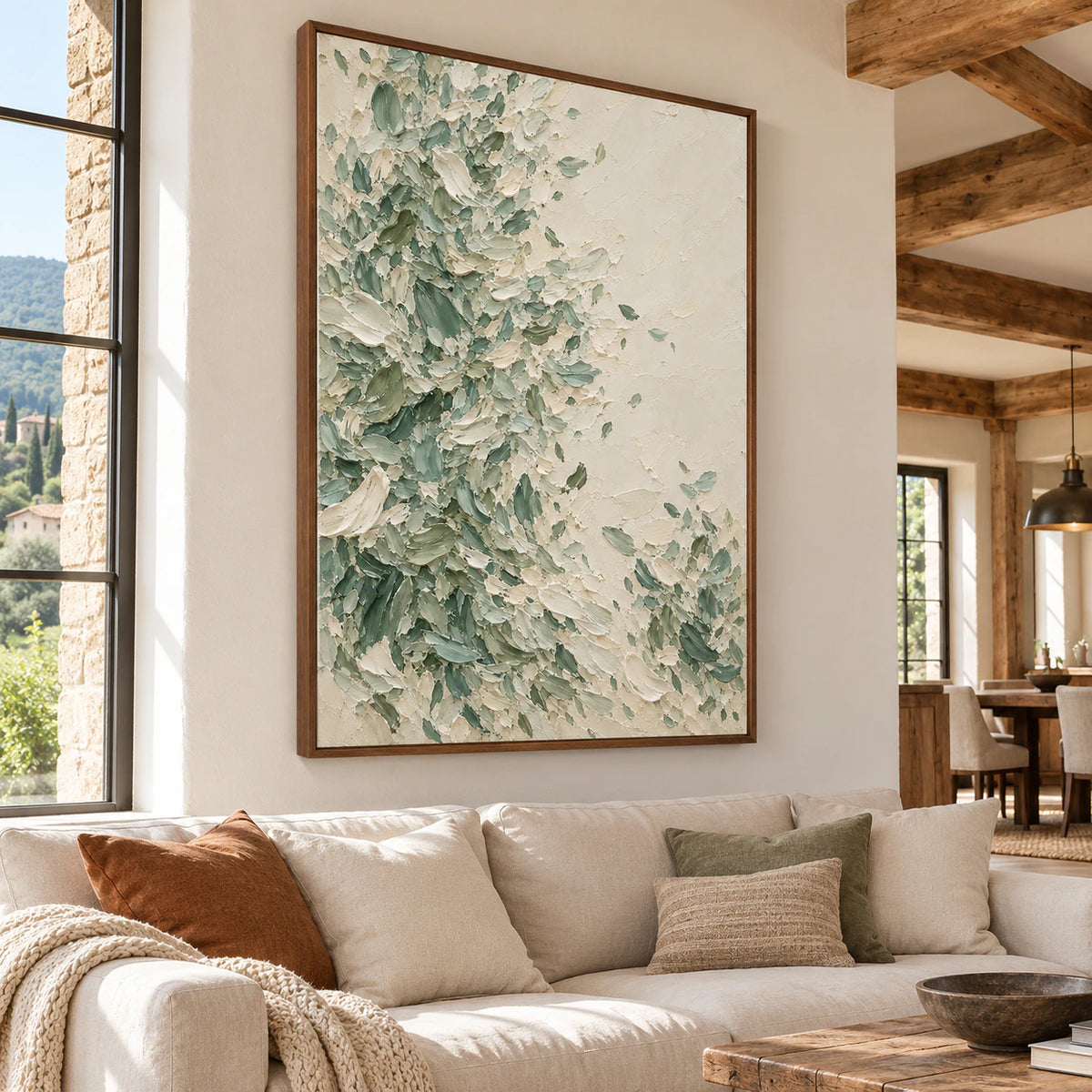 Large vertical abstract painting above a restrained pale sofa in a bright living room, with daylight and open space around it.