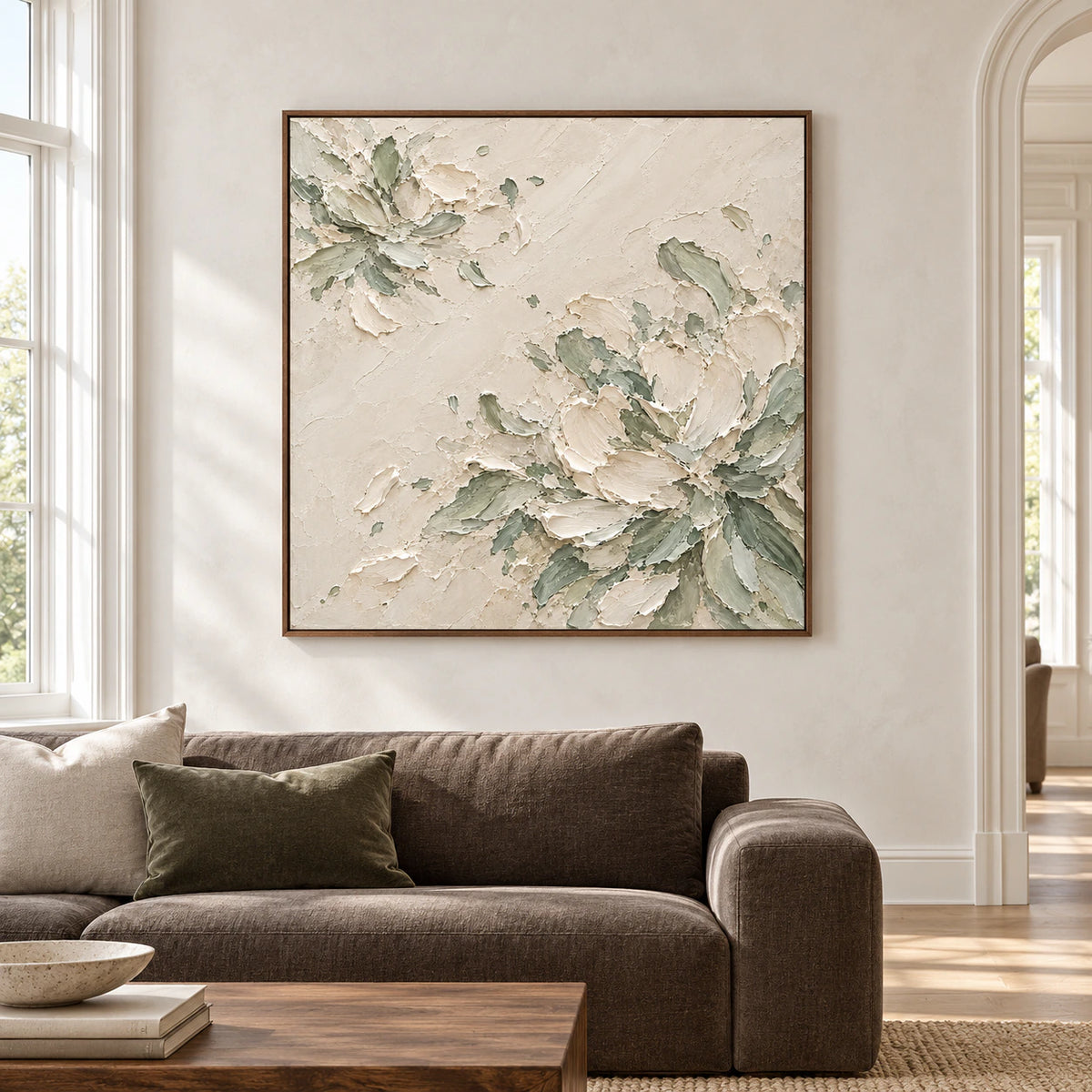 Large square framed artwork with raised ivory petals and muted sage rosettes displayed straight-on in a bright, spacious living room.