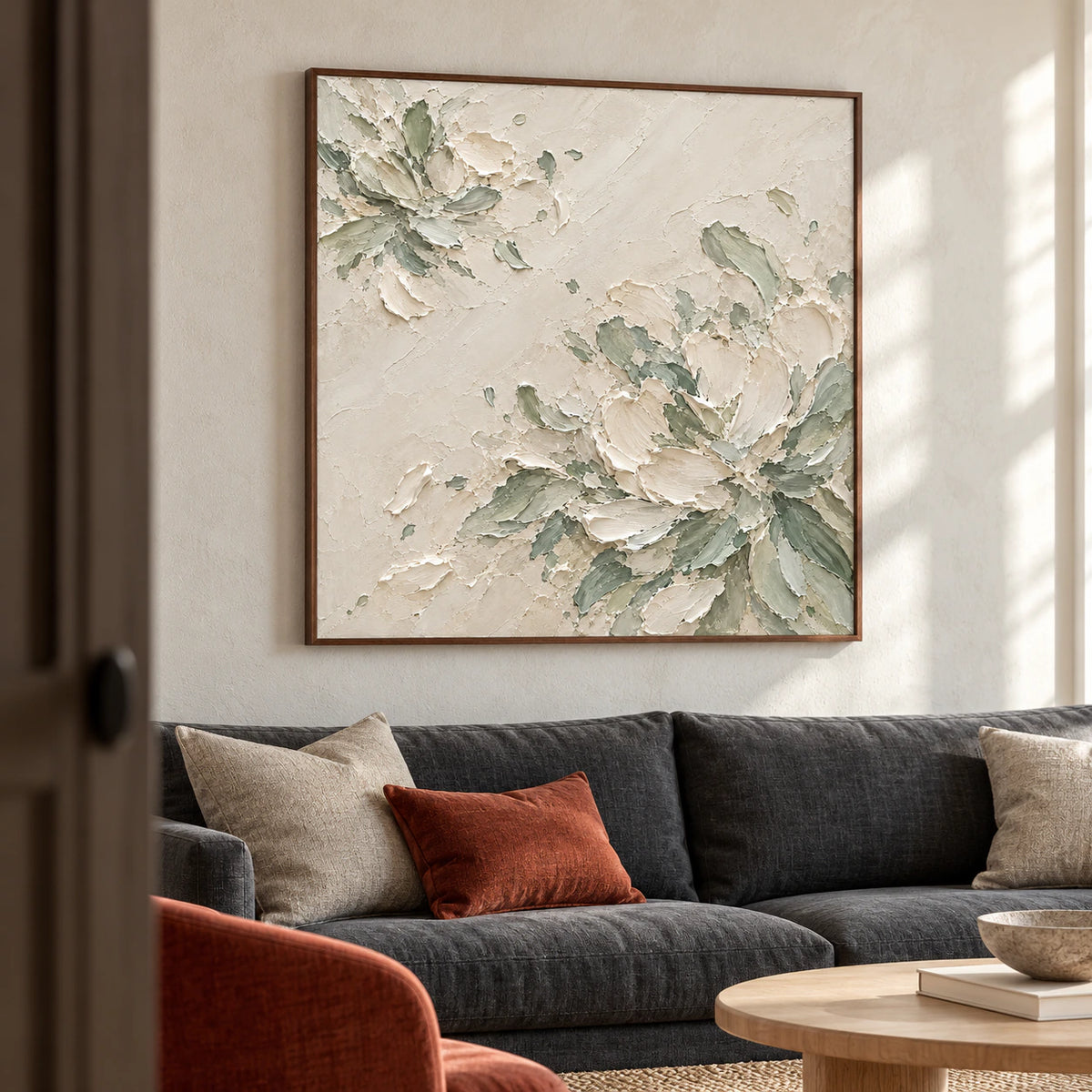 Large square floral abstract centered above a charcoal linen sofa in a bright living room with pale stone walls and natural daylight.