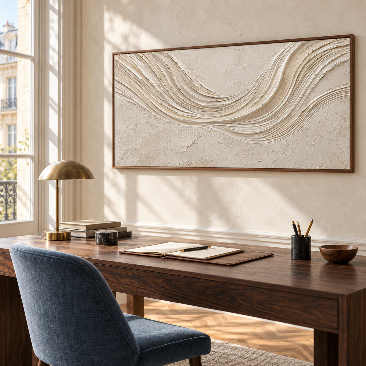 Right oblique view of the horizontal ivory abstract painting behind a dark wood desk, with a slate-blue chair and pale walls in a bright home office.