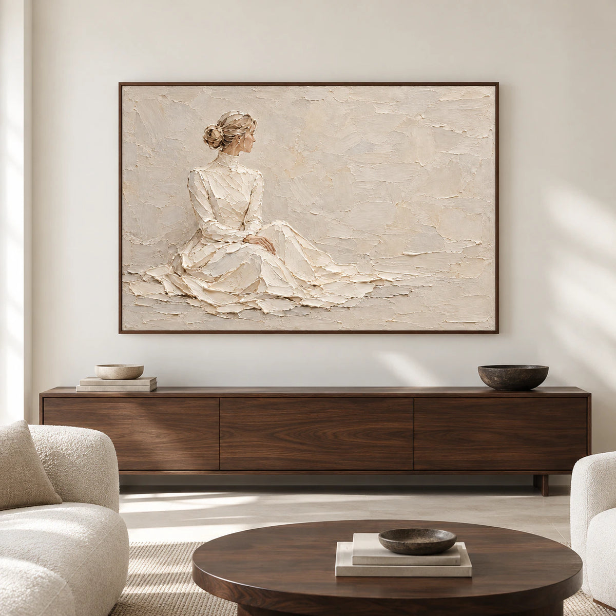 Large horizontal artwork of a seated figure in ivory and sand displayed straight-on above a low console in a spacious, bright architectural living room.