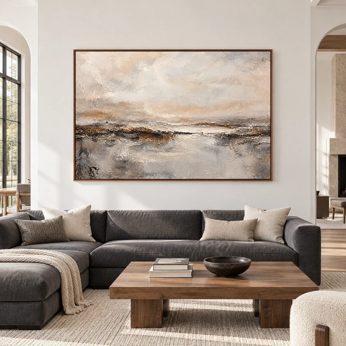 Large horizontal abstract painting with a pale clouded field and rugged dark horizon displayed prominently in a spacious room.