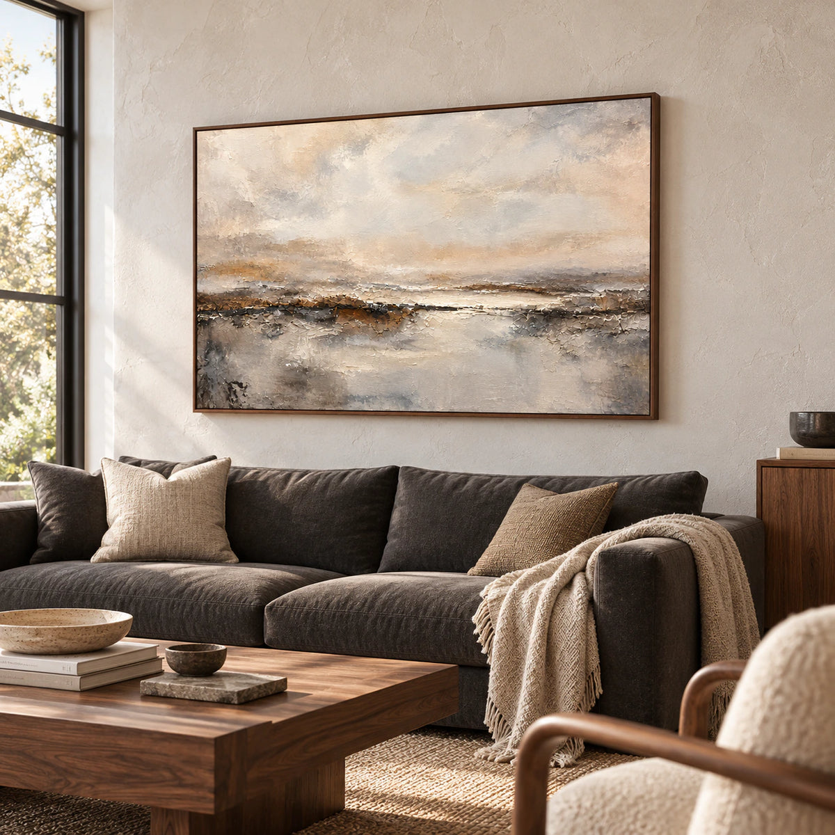 Large textured abstract landscape above a charcoal sofa in a bright living room with pale walls and natural daylight.