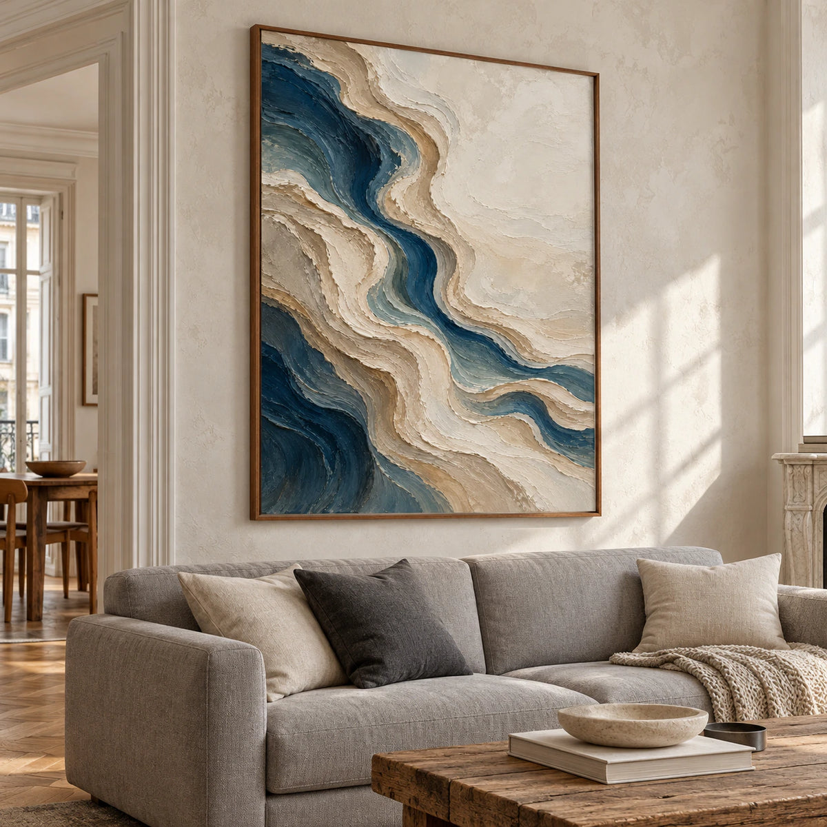 Large vertical blue and ivory abstract painting displayed above a neutral sofa in a bright living room.
