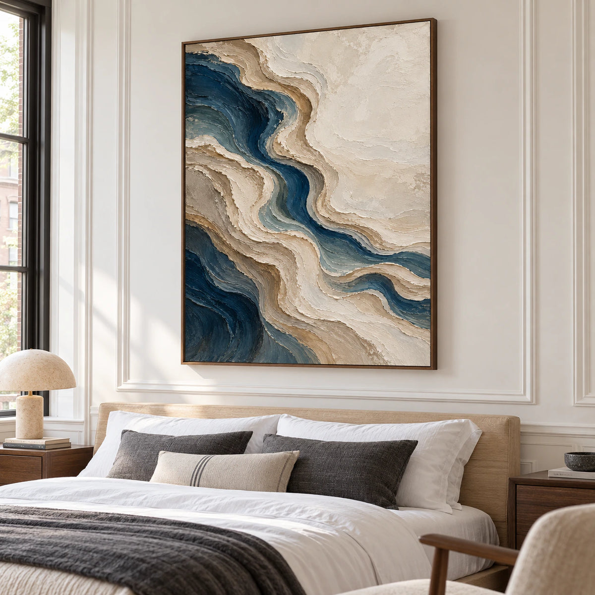 Large blue and warm neutral abstract painting above a low bed in a quiet, daylight-filled bedroom.