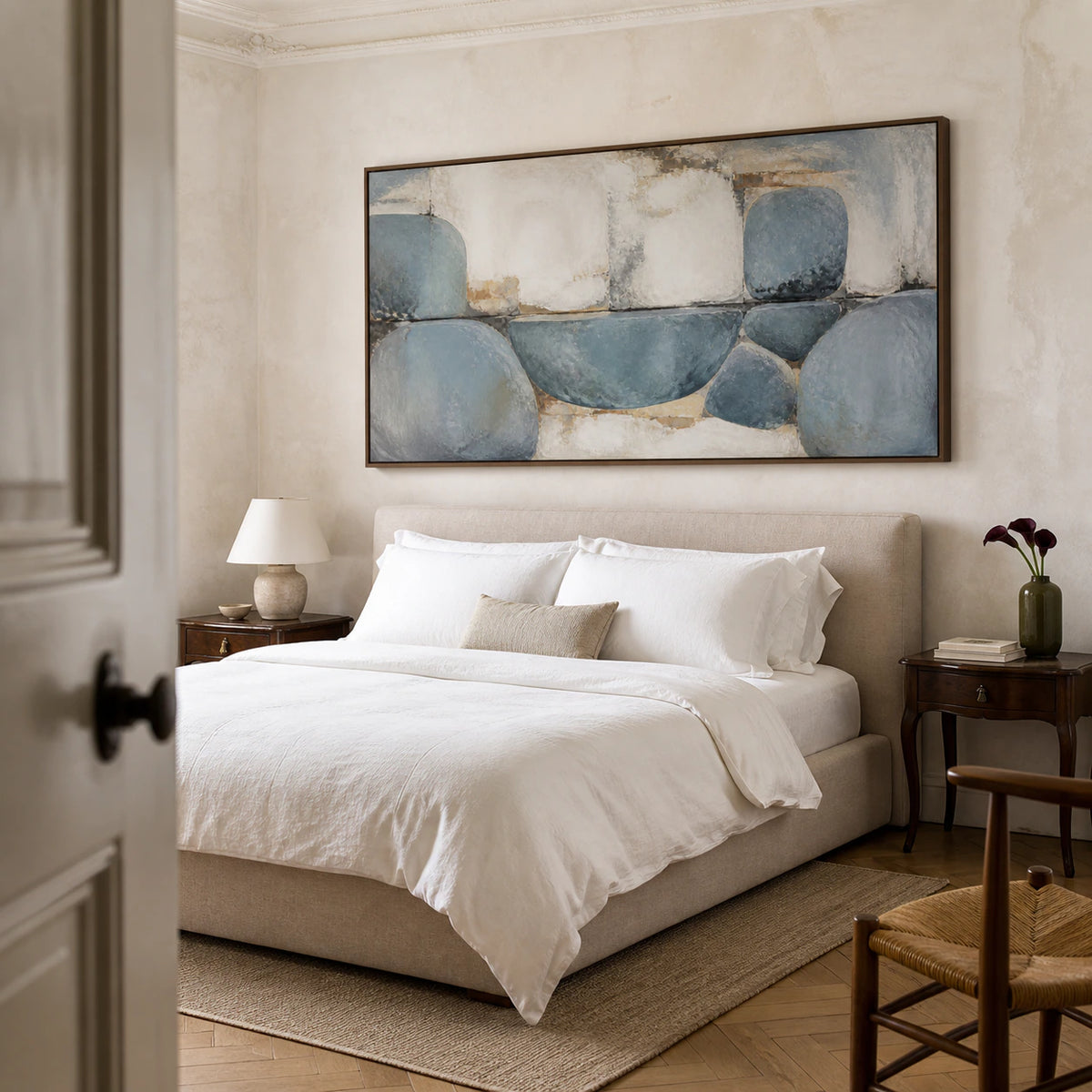 Quiet bedroom with the blue-grey abstract painting presented above a restrained neutral setting.