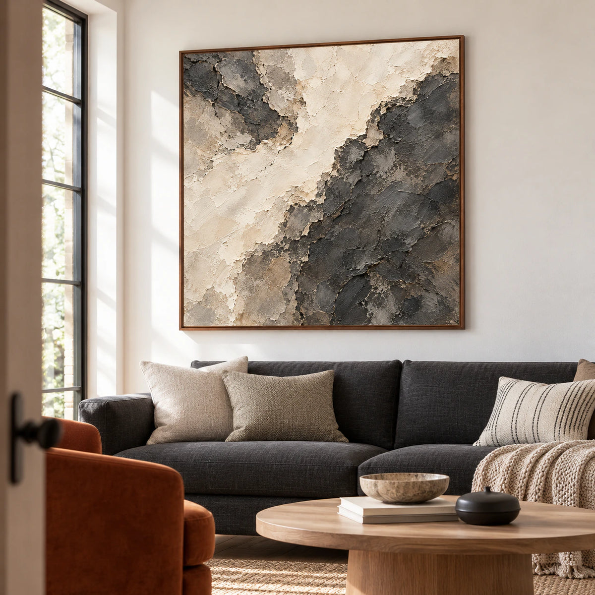 Soot-Divide above a charcoal sofa in a bright, open living room, viewed slightly from the left at seated eye level.