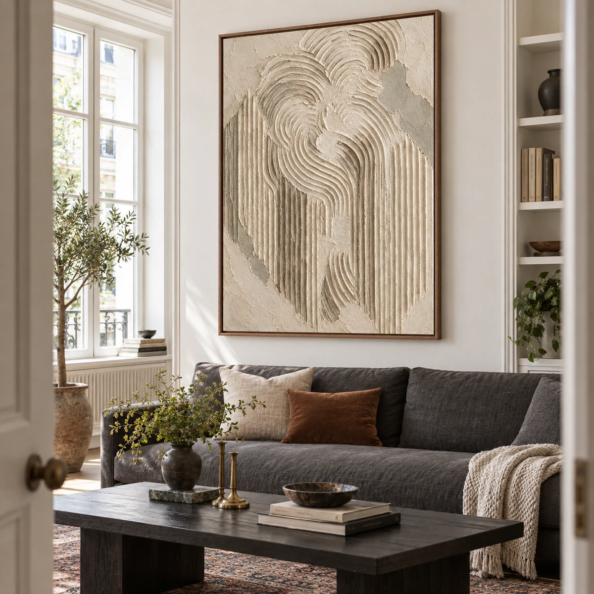 Vertical textured ivory artwork above a restrained sofa in a bright contemporary living room.