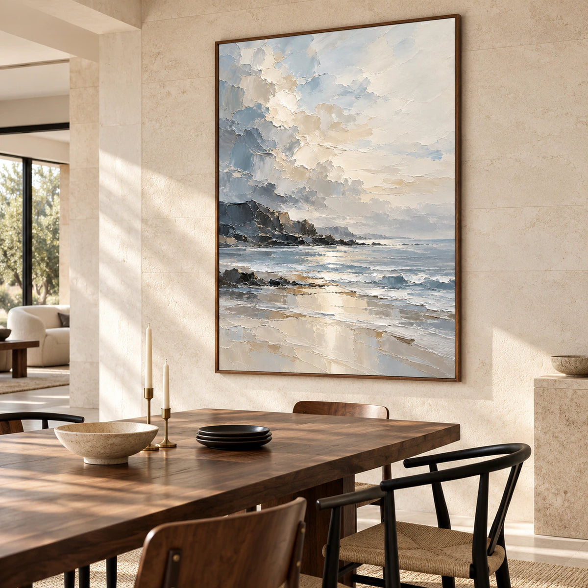 Coastal painting on a light limestone wall above a dark walnut dining table with black chairs and minimal tableware, viewed from the right in side daylight.