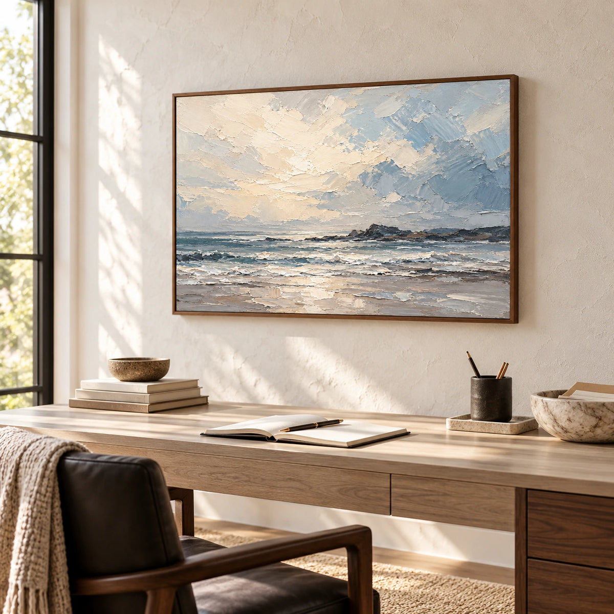 Seascape painting above a pale desk with a dark chair in an airy home office and reading space, viewed from the right at standing height.